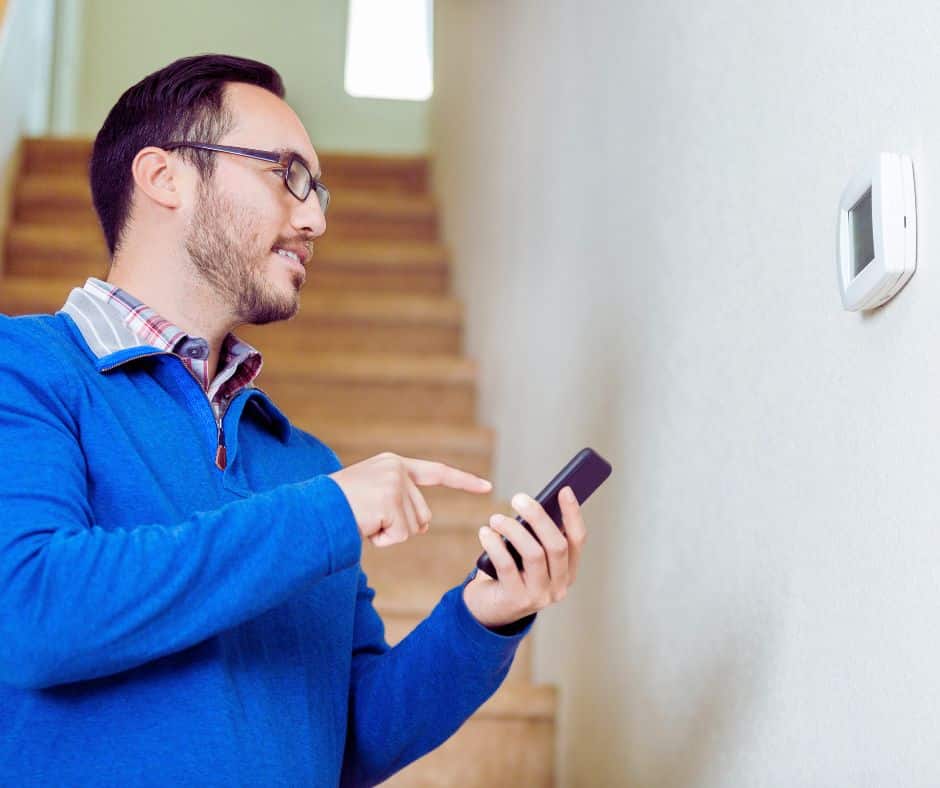 Man setting smart thermostat